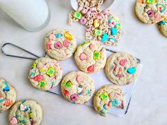 cookies with cereal and marshmallows are on a table next to a cup of milk