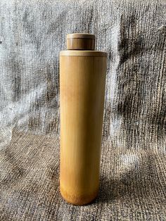 a wooden bottle sitting on top of a cloth covered bed sheet with the lid down