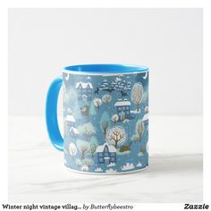 a blue and white coffee mug with winter village designs on the front, sitting on a marble surface