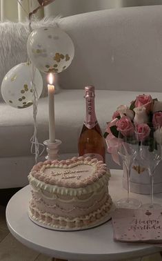 a table topped with a cake next to a bottle of wine and flowers on top of a table