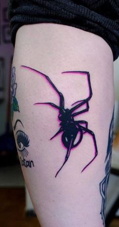 a woman's leg with a spider tattoo on the side of her thigh and an eye