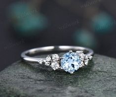 an engagement ring with a blue topazte and white diamonds in the center on a rock