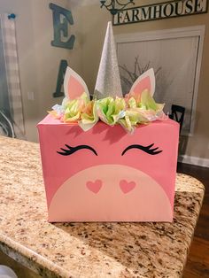 a pink bag with a unicorn's face and flowers on it sitting on a counter