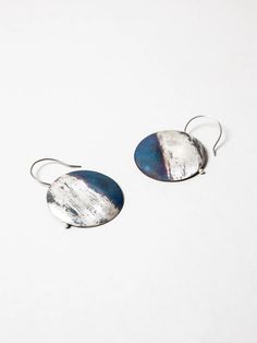 The Blue Silver Earrings from artist Shima Hotta feature a slightly rounded shape with a textured finish. The blue and purple tint is created by applying a flame to the silver and brass material, and natural oxidation. These colors continue to change over time, evolving along with the wearer. About Shima JewelryNagano- Esoteric Jewelry, Brass Material, Blue And Silver, Jewelry Inspiration, Silver Earrings, Blue And Purple, Silver Rings, Hoop Earrings, Brass