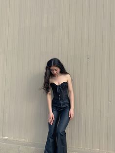 a woman standing in front of a wall with her hands on her hips wearing black leather pants