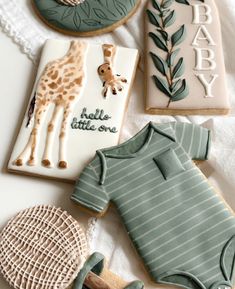 baby shower cookies and cookie decorations on a white tablecloth, including ones like a giraffe