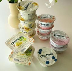 several different flavors of ice cream on a white table with a vase and flower in the background