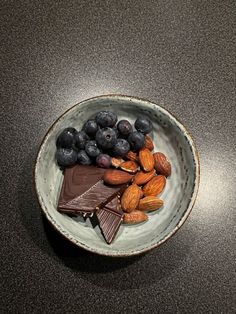 a bowl filled with nuts, chocolate and blueberries