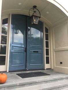 two blue doors with one light on and the other in an orange pumpkin sitting next to it