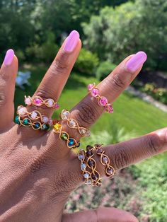 a woman's hand with several rings on it, including an open ring and two different colored stones