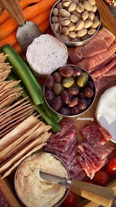 an assortment of meats, vegetables and cheeses on a platter with utensils