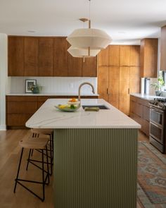 a large kitchen with an island in the middle and wooden cabinets on both sides, along with two bar stools