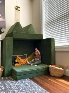 a small child is sitting in a green bed with a stuffed animal on the bottom