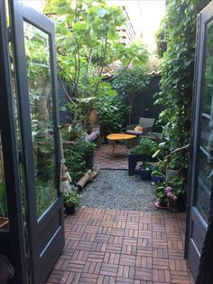 an open door leading to a small patio with potted plants on either side and a table in the middle