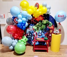 a bunch of balloons that are on the ground near a table with an iron man and captain america sign