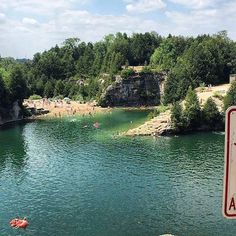 a body of water surrounded by trees and people swimming in the water with life jackets on