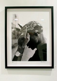 a black and white photo of a man holding his hand up to his face while wearing a hat