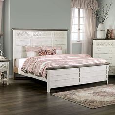 a white bed sitting on top of a wooden floor next to a dresser and mirror