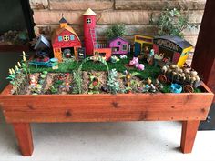 a wooden planter filled with lots of plants and small toy farm animals on top of it