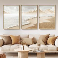 three paintings hang on the wall above a couch in a living room with two tables