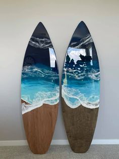 two surfboards are standing next to each other in front of a wall with an ocean scene painted on it