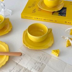 a yellow tea set on top of a table next to some papers and cheese slices