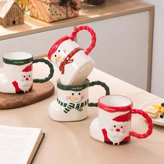 three coffee mugs are stacked on top of each other with snowmen painted on them