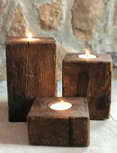 three wooden blocks with lit candles in them