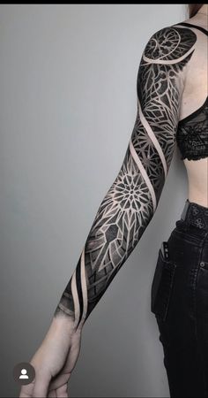 a woman's arm with black and white tattoos on her left arm, showing the intricate