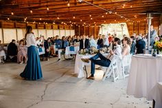 a group of people sitting around tables in a room with white clothed tables and chairs