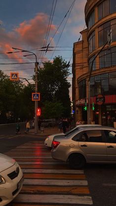 two cars are stopped at an intersection in the city as the sun is going down