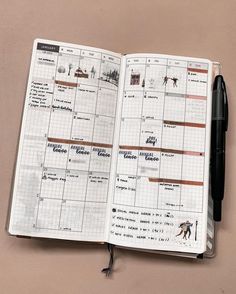 an open planner is shown on top of a pink surface with a pen in it