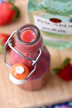 a jar filled with liquid sitting on top of a table next to some strawberries