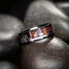 a wedding band with an image of a horse is shown on top of some rocks