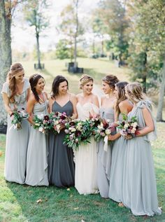 a group of women standing next to each other on top of a lush green field