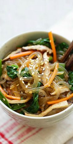 a bowl filled with noodles and vegetables on top of a table