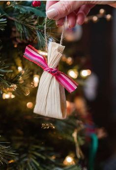 someone is holding an ornament in front of a christmas tree