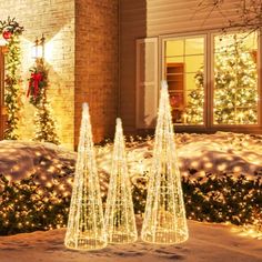 three lighted christmas trees in front of a house