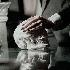 a person with their hand on a fake skull