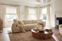 a living room filled with furniture and a fire place in front of a window covered in curtains