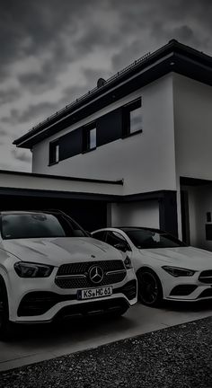 two white cars parked next to each other in front of a house