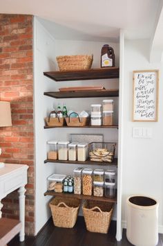 an organized pantry with baskets, food and other items on the shelving in front of a brick wall