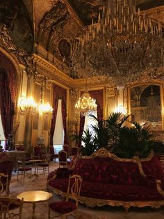 an ornately decorated room with chandeliers and red velvet couches