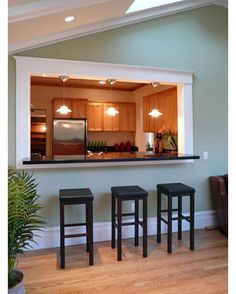 three stools sit in front of a bar with a television on the wall behind it