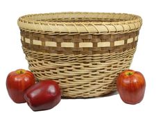 two red apples sitting next to a wicker basket