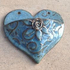 a blue heart with a rose on it is sitting on the ground in front of a wall