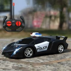 a toy police car is shown on the ground next to a remote control device that looks like it's in action