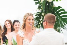 a bride and groom smile at each other during their wedding ceremony