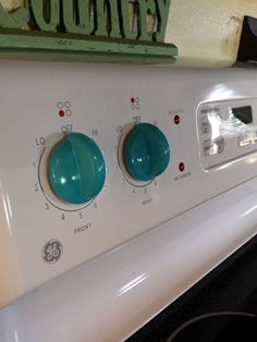 a white stove top oven sitting inside of a kitchen next to a green sign that says country