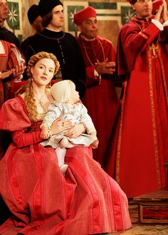 a group of people dressed in red and black standing next to each other with one holding a baby